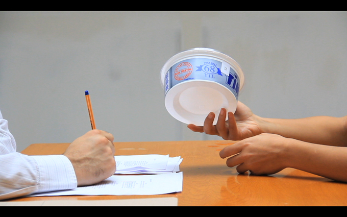 woman holds empty plastic yoghurt cup towards the man